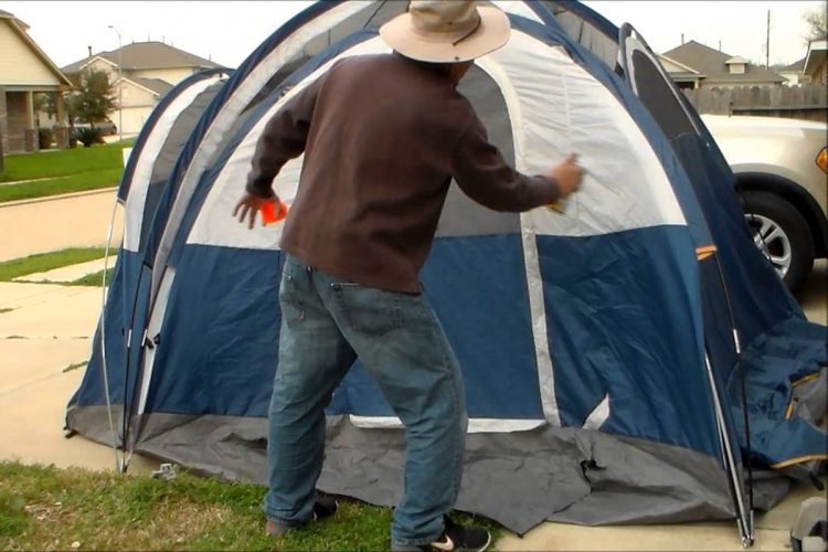 Guy waterproofing a tent