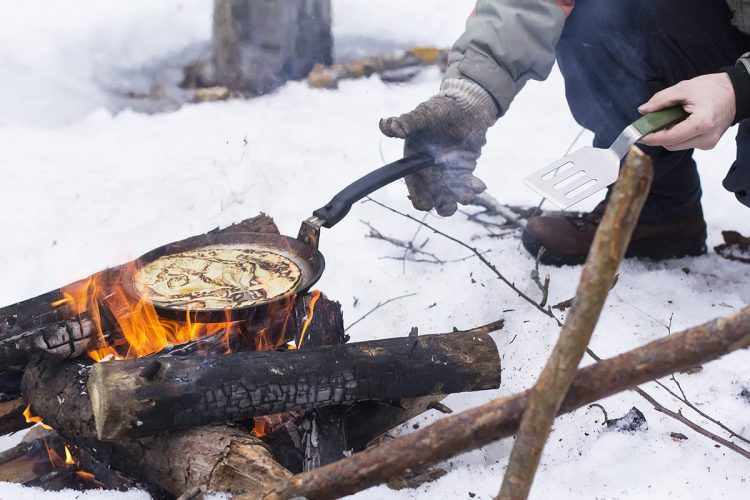 Pancakes cooking over an open camp fire in winter