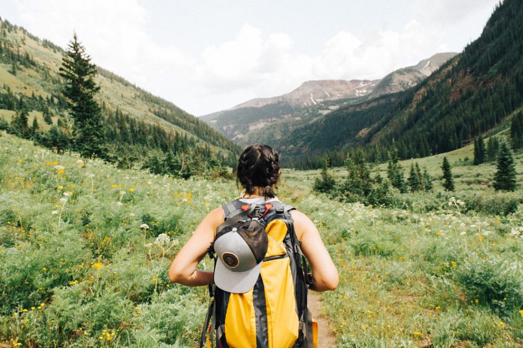 Lady walking through valley with a yellow backpack on