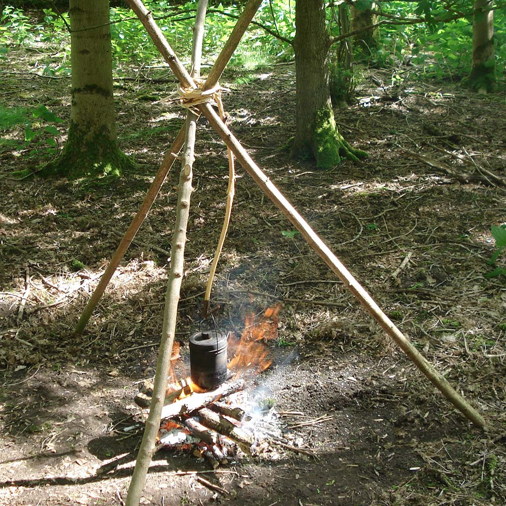 Boiling water over a camp fire using a tripod to suspend the pot